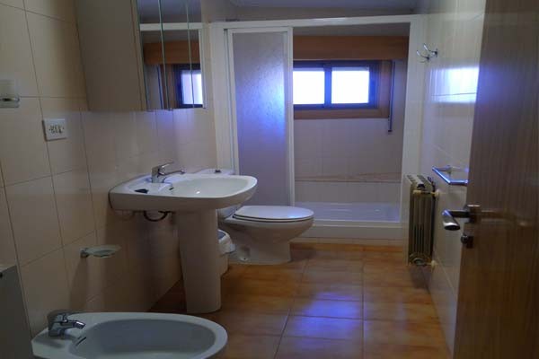 baño, con ducha grande, inodoro, lavamanos, vide y un mueble con un surtido de toallas