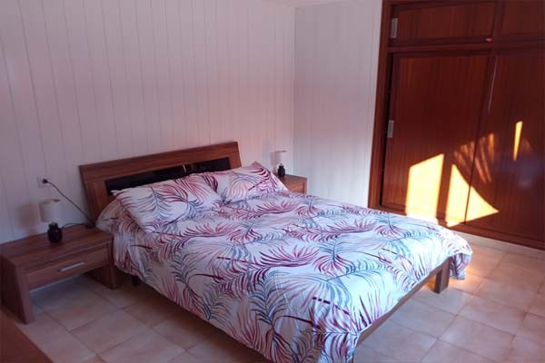 una habitación doble, con  dos juegos de ropa de cama, dos mesillas,sus lamparas y armario